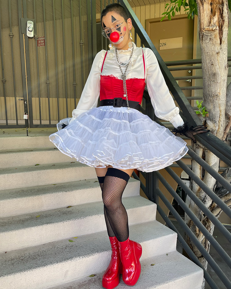 A person wearing a clown Halloween costume with red nose and white tutu