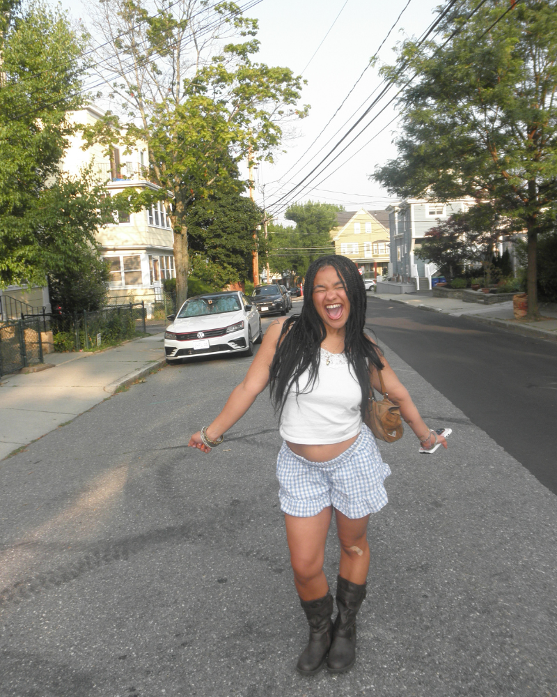 woman standing in middle of empty street smiles with arms outstretched