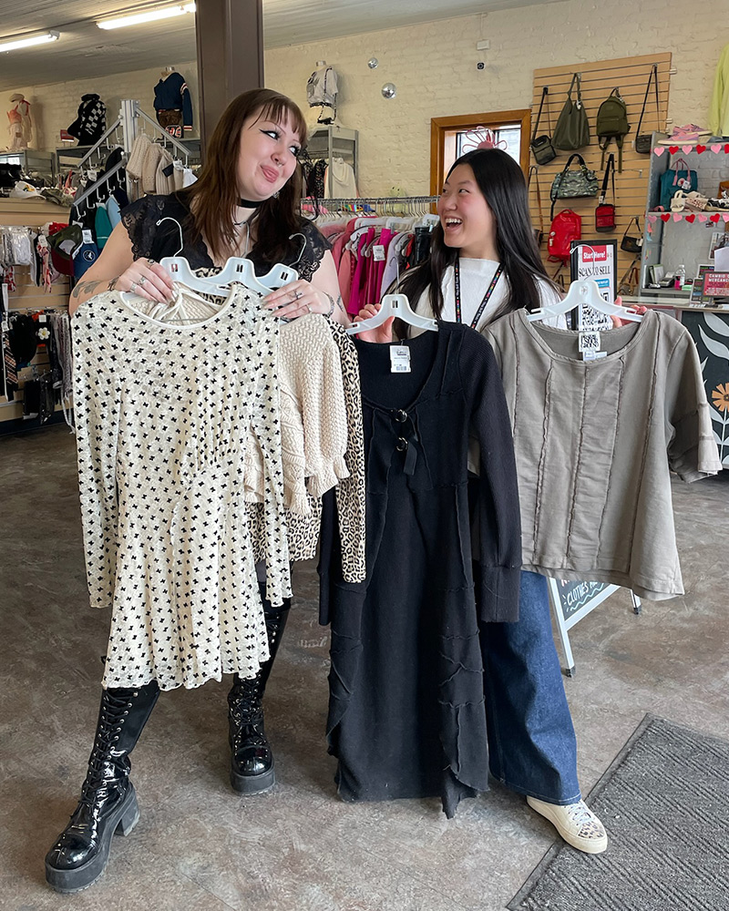 Two employee friends holding clothes