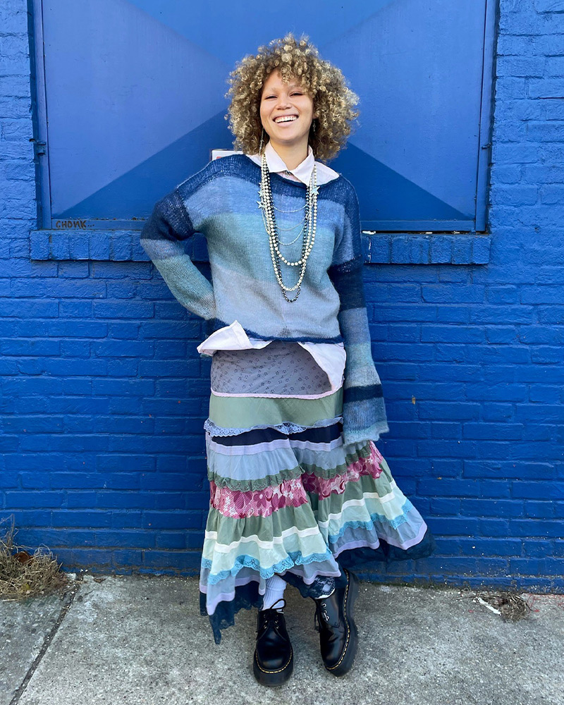 Employee Zoey posing against a blue wall