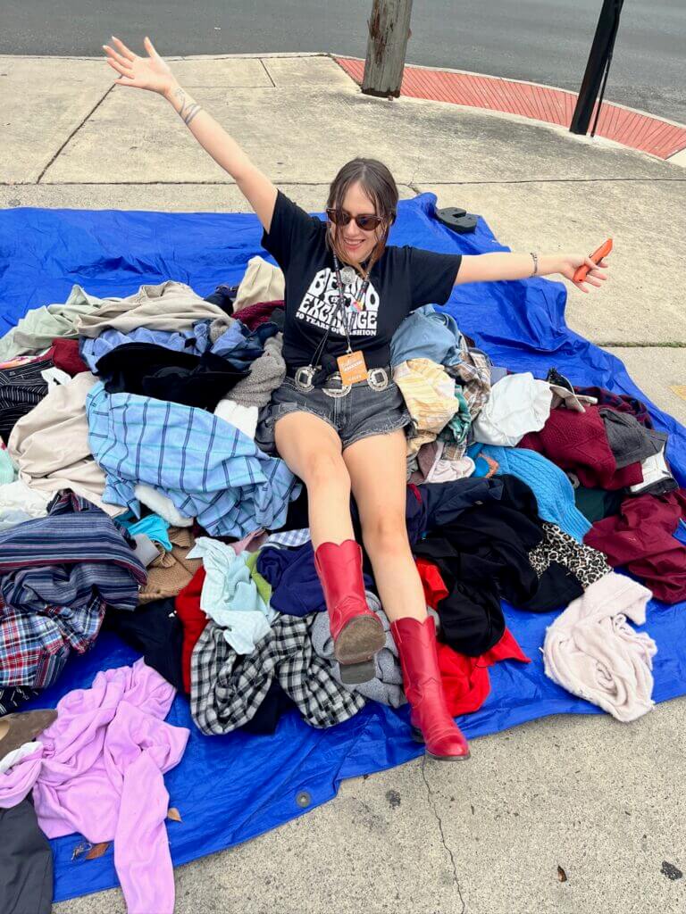 shoppers laying in pile of clothes celebrating