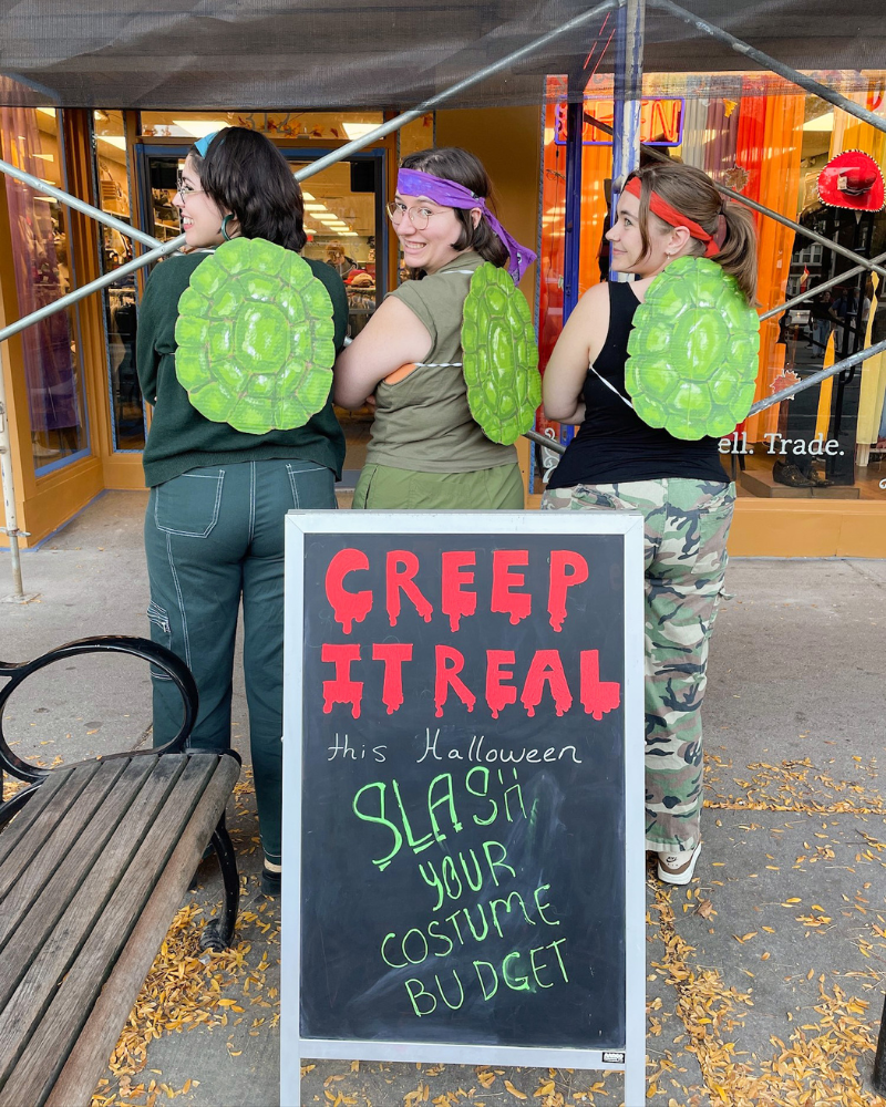 10 Group of Buffalo employees wearing fake turtle shells on their backs and posing next to a spooky sandwich board