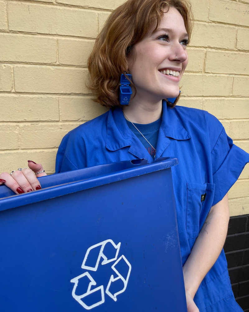 person holding blue recycling bin