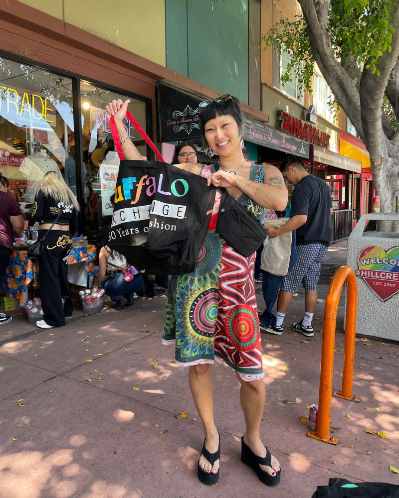 $1 Sale customer smiling and holding a Buffalo tote outside the store.