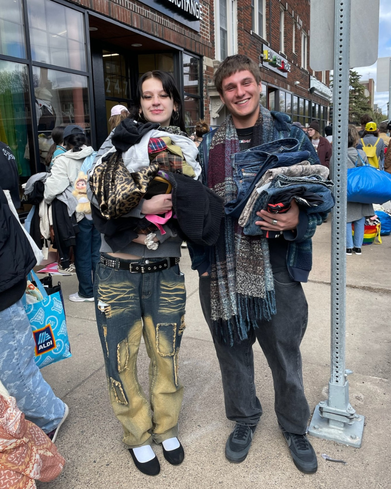 $1 Sale customers smiling and holding stacks of clothing.