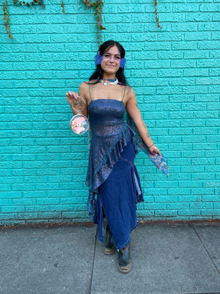 A woman dressed up as a fish for Halloween in a flowy, sequined top and long denim skirt.