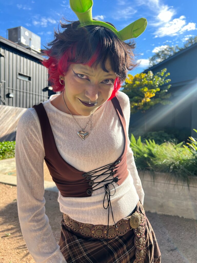 A person dressed up as Shrek smirking at the camera.